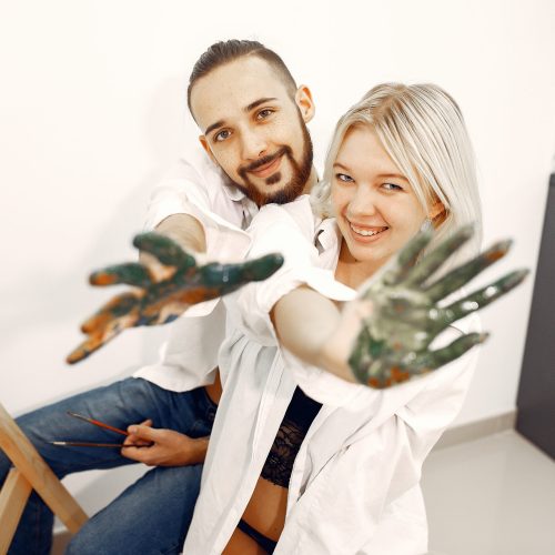 Couple in an art studio. Blonde in a shirt.  Pair at home.